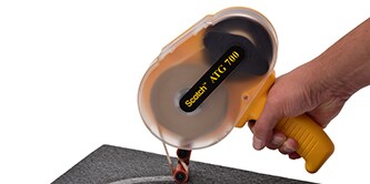 Một công nhân dán băng bằng dụng cụ tháo băng cầm tay trong khi dán băng trong khi tháo lớp lót
