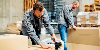 Image of masked workers in a clean white room keeping track of stacks of packages
