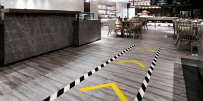Image of a floor with traffic lane marked with black-and-white stripe tape and traffic direction marked with yellow tape

