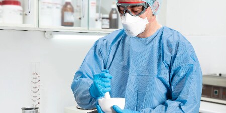nhân viên chăm sóc sức khỏe đeo PAPR có mũ trùm đầu đang giúp đỡ bệnh nhân
