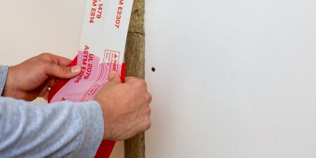 A worker applies 3M™ Fire and Water Barrier Tape to a construction joint
