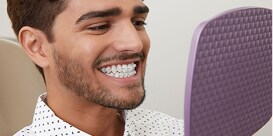 Người đàn ông nở nụ cười, cho thấy màu sắc tự nhiên của mắc cài sứ 3M trong suốt.
