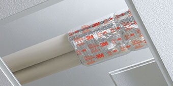 3M™ Fire Barrier Plenum Wrap 5A+ installed around pipes above a drop ceiling
