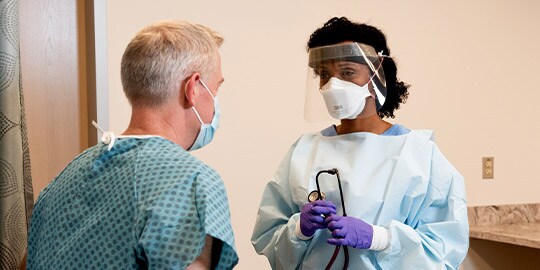 Chuyên viên y tế đang sử dụng PPE (trang thiết bị bảo hộ cá nhân) khi tiếp xúc gần với bệnh nhân
