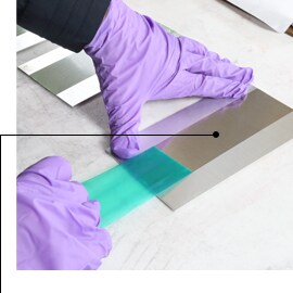 Hình ảnh đôi tay đeo găng đang tháo băng keo 3M™ Polyester Tape 8992, để lại đường che sắc nét và không có cặn keo.