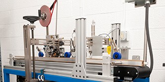 Một chiếc máy phức tạp được sử dụng để dán các bộ phận khi chúng chạy qua bên dưới trên băng chuyền
