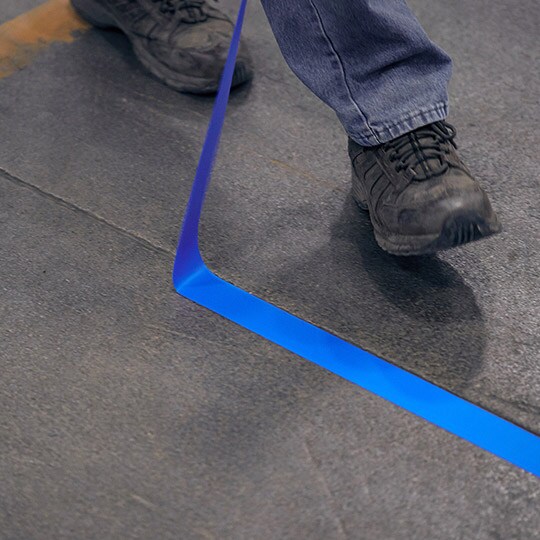 Person removing blue tape from facility floor
