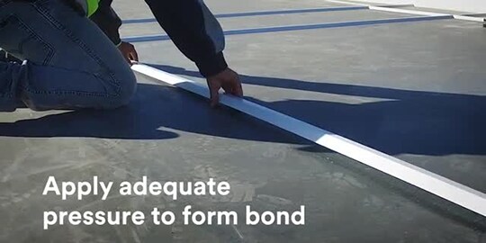 Video still of a construction worker laying down reveals with screen text “Apply adequate pressure to form bond”
