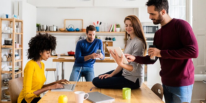 Những người trong văn phòng cầm nhiều thiết bị điện tử tiêu dùng gồm máy tính xách tay, máy tính bảng và điện thoại thông minh.
