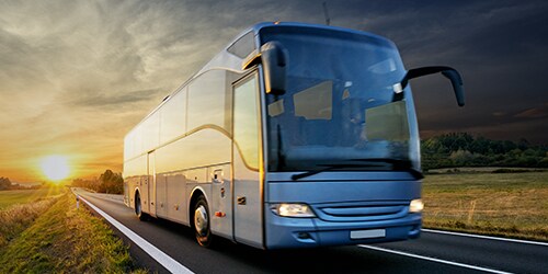 Xe buýt lắp rắp hiện đại đi trên đường cao tốc dưới hoàng hôn