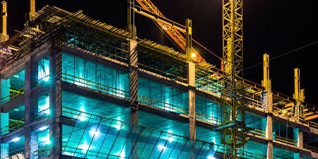 Một công trường vào buổi tối với giàn giáo và cần cẩu.
