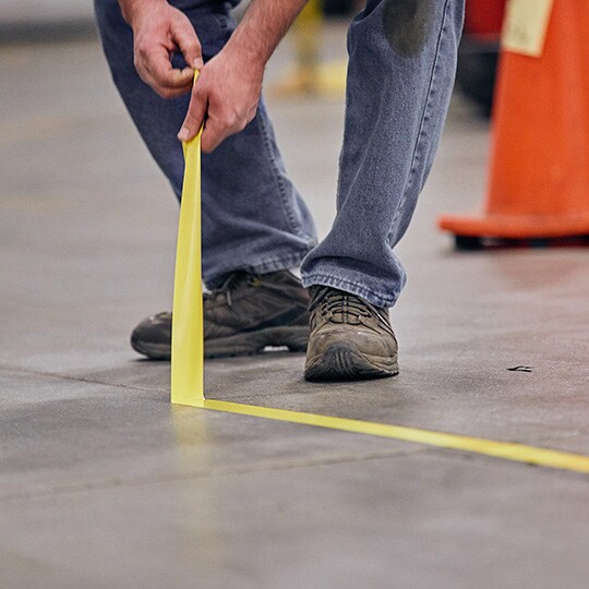 Person cleanly removing floor tape from facility floor