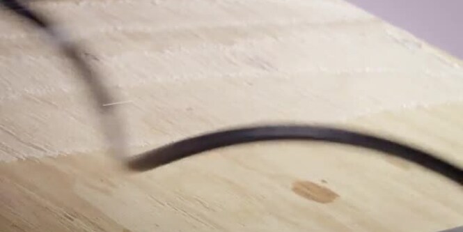Video still of 3M™ HoldFast 70 Spray Adhesive being sprayed on plywood before rolling out roofing felt
