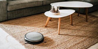 Phòng khách trải thảm với bàn cà phê hiện đại và máy hút bụi tự động.
