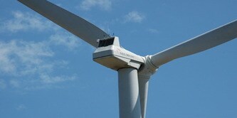 Cận cảnh bộ cánh quạt và rotor của tuabin gió dưới bầu trời xanh.
