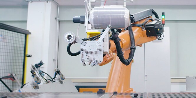 Hình ảnh một bộ cánh tay robot với đầu dán giữ một cuộn băng keo cuốn ngang rộng

