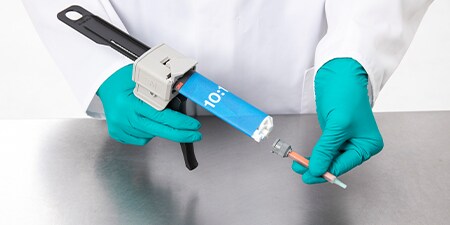 Một công nhân đeo găng gắn một đầu trộn vào keo Duo Pak tỷ lệ 10-1 trong một dụng cụ bôi keo EPX
