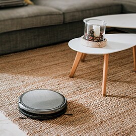 một robot hút bụi không dây đang làm sạch thảm phòng khách.