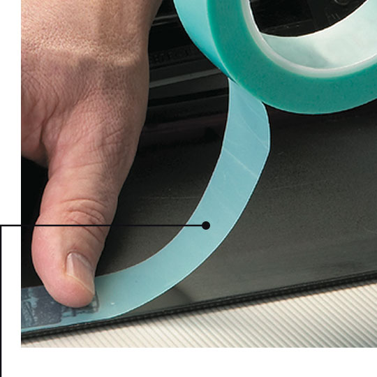 Hình ảnh một công nhân đang áp dụng băng keo che chắn không chứa silicone lên một bộ phận.