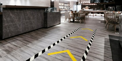 Image of a floor with traffic lane marked with black-and-white stripe tape and traffic direction marked with yellow tape
