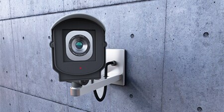 Camera giám sát gắn trên bức tường bê tông màu xám.
