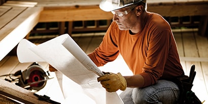 A worker reviews a blueprint before starting