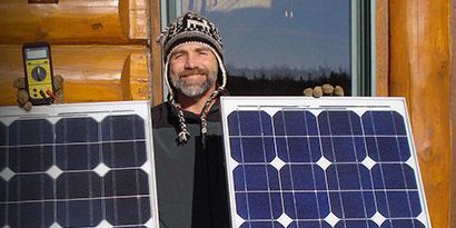 3M scientist Tim Hebrink holding the solar panels that have helped him generate about 80 percent of his home’s energy.

