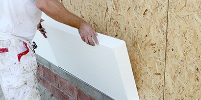 Workers using spray adhesive to install insulation
