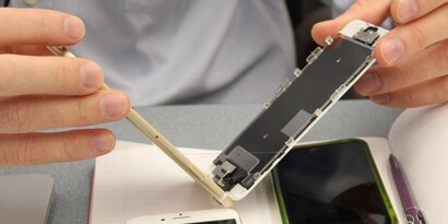 A person holding two pieces of a phone, the face and body, showing the reworkability of 3M's electronics bonding solutions.
