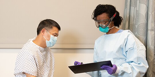 Bác sĩ mặc PPE khi nói chuyện với bệnh nhân
