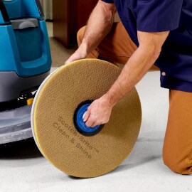 Person installing Scotch-Brite clean and shine pad on machine