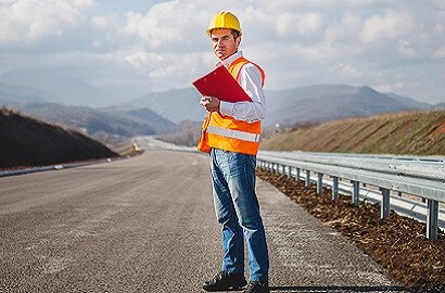 A person in hard hat holding a red folder.