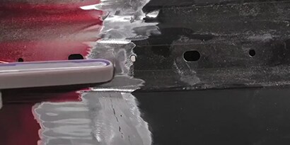 technician removes steel part from car
