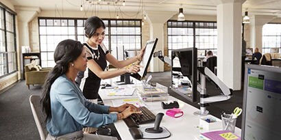 Two women work in an open office environment
