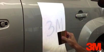Một thợ dán đồ họa đang làm phẳng lớp dán đồ họa 3M trên xe ô tô.

