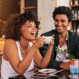 Smiling man and smiling woman holding a white coffee cup