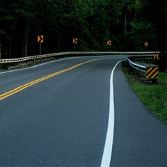 A road with a guard rail and trees
