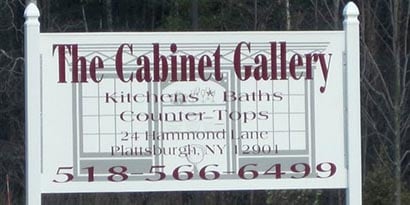 Một biển trắng lớn được bọc bằng phim màu 3M ghi chữ The Cabinet Gallery và số điện thoại bằng phông chữ màu đỏ tía
