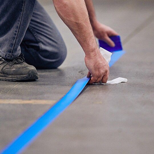 Person applying 3M floor tape to facility floor