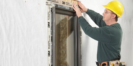 A worker applies 3M™ All Weather Flashing Tape 8067 around a window
