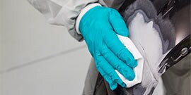 technician cleans bumper repair area to ensure coating adhesion